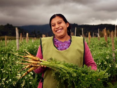vrouwelijke ondernemer Sandra Xiquin Chiroy uit Guatemala, 28 jaar in haar veld met poerend met wortelen