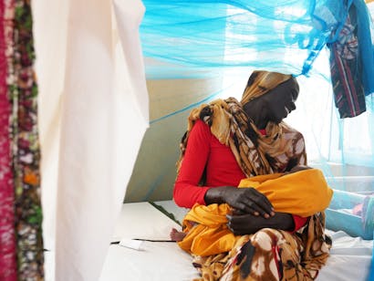 Een Soedanese moeder lacht liefdevol naar haar kind
