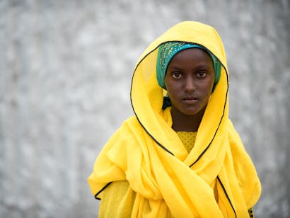 Een jonge vrouw in een fel geel gewaad kijkt in de camera