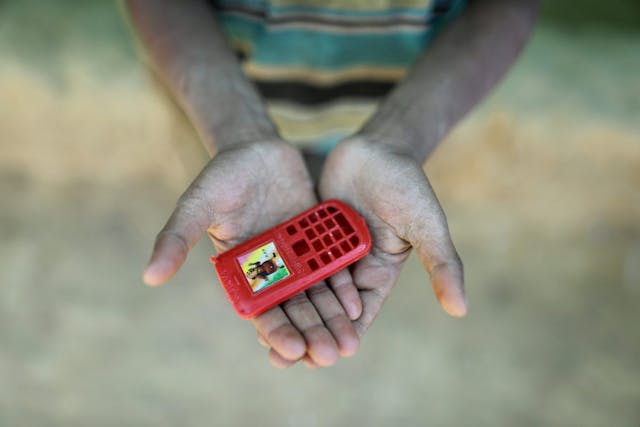 Handje van een jongetje gevlucht uit Myanmar nu in BAngladesh met een speelgoedtelefoon