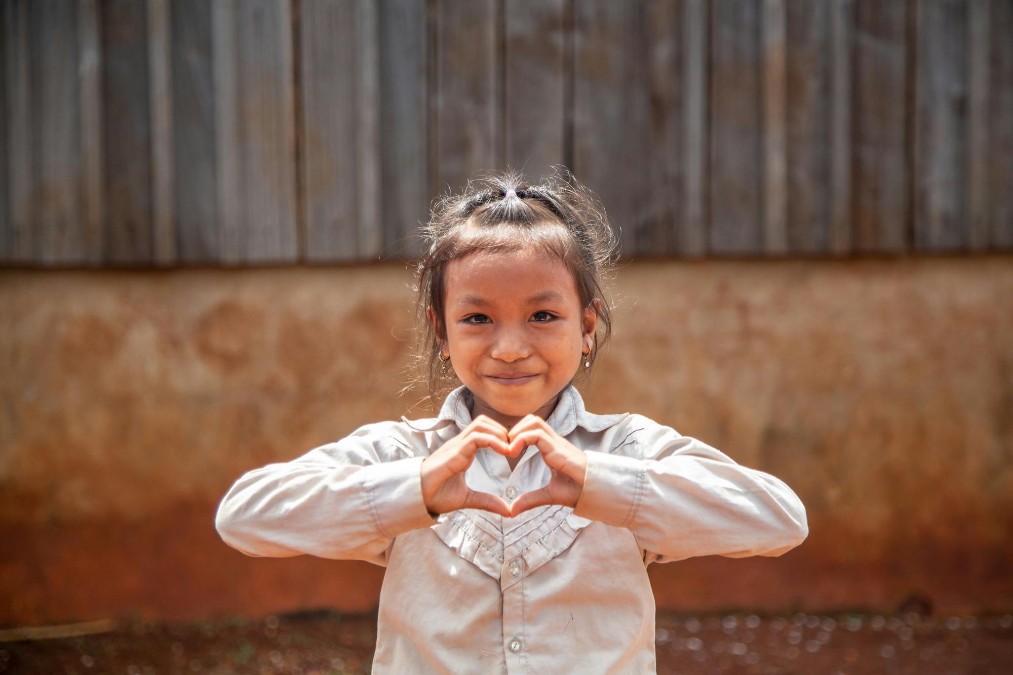 Meisje uit Cambodja die met haar handen een hartje vormt