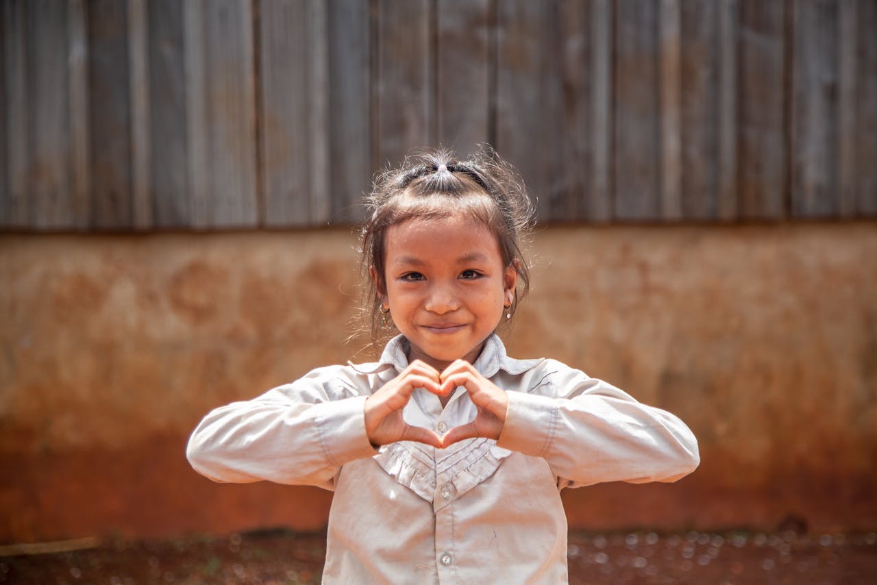 Meisje uit Cambodja die met haar handen een hartje vormt