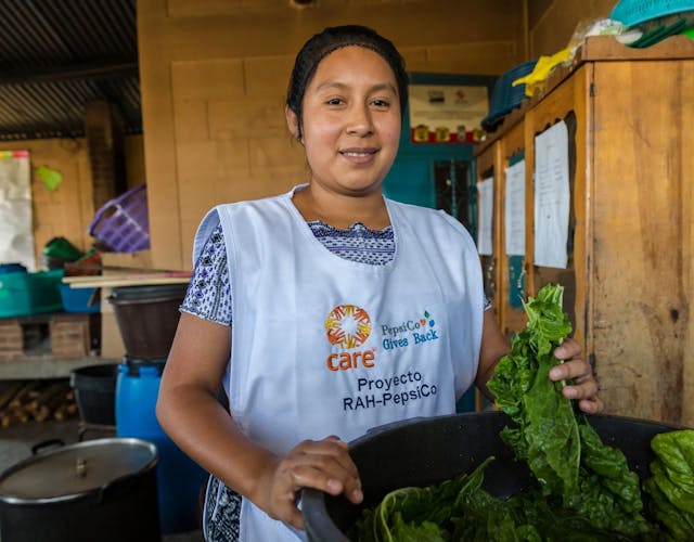 Een vrouw in Guatemala is eten aan het bereiden in een keuken en ze lacht naar de camera