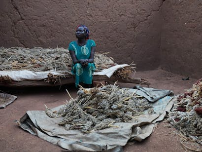 Een Zuid-Sudanese vrouw zit bij haar oogst